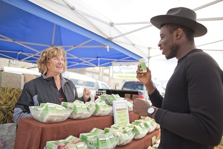 A man speaking with a farmer's market vendor